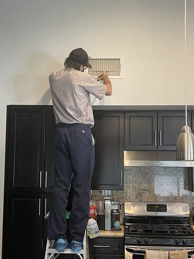 Technician inspecting an air vent during HVAC service in Socorro